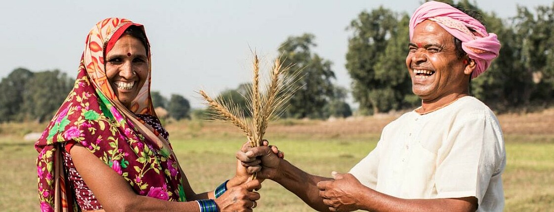 The picture shows a woman and a men showing crops