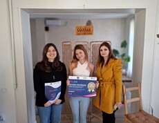 Three women stand side by side in a room, holding a certificate and a folder.