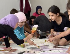 Children work together on large sheets of paper during a creative workshop activity in Lebanon.