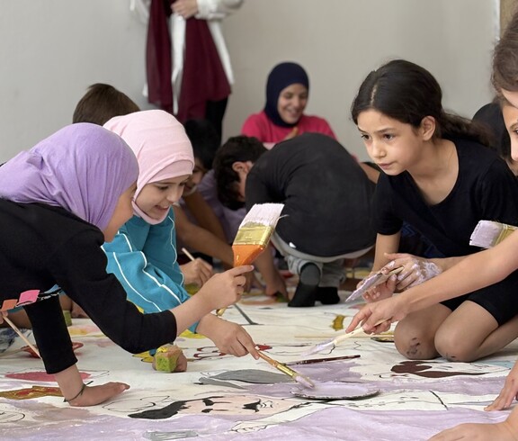 Children work together on large sheets of paper during a creative workshop activity in Lebanon.