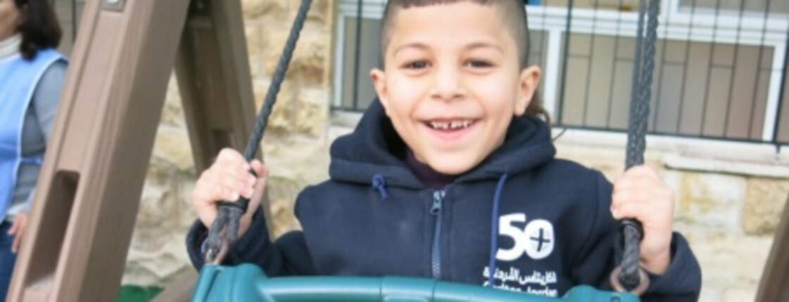 Omar on the swing A boy on a swing, smiling into the camera