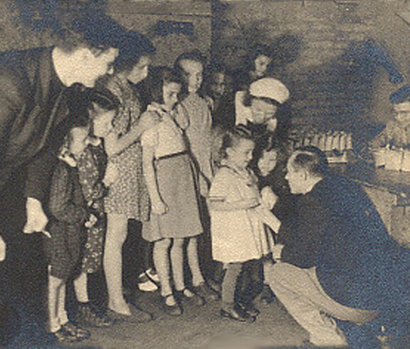Children stand in line and receive sugar from Caritas staff—a scene from 1946