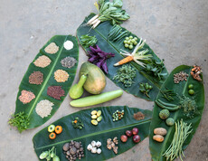 Various vegetables, fruits and seed varieties laid out on large banana leaves