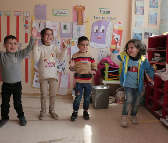 Six children take part in a coordinated group activity in a brightly decorated classroom in Lebanon.