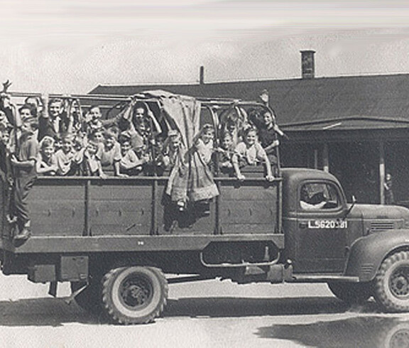An open-bed Caritas truck with numerous children on the bed during a recreational trip in 1947
