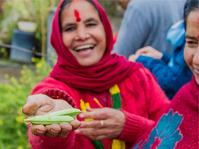 Das Bild zeigt eine Kleinbäuerin mit Saatgut in der Hand
